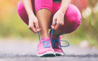 A woman in pink pants tying her shoes.