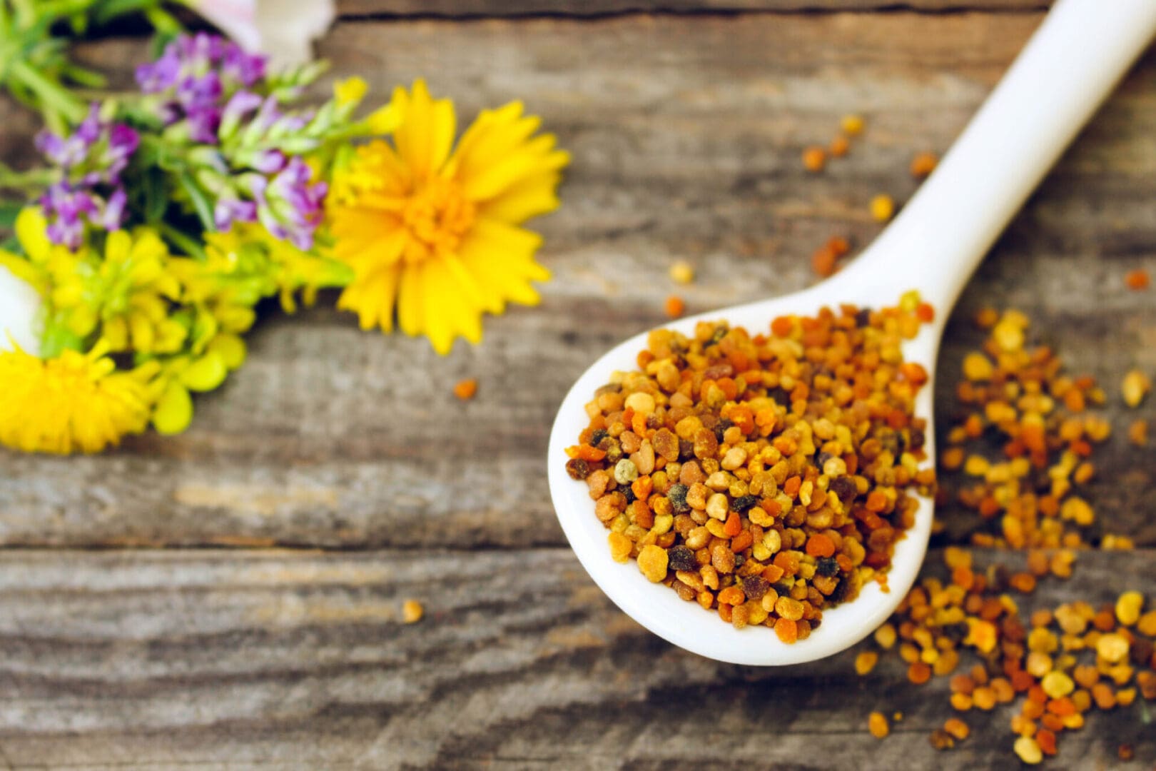 Spoon of bee pollen on wooden background.