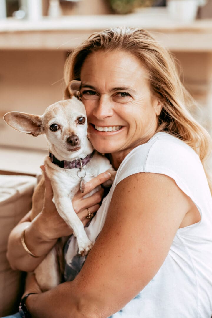 Woman smiling while holding a small dog.