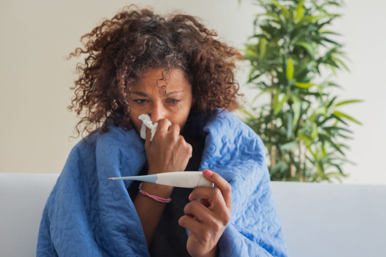 Woman with a cold, holding a thermometer.