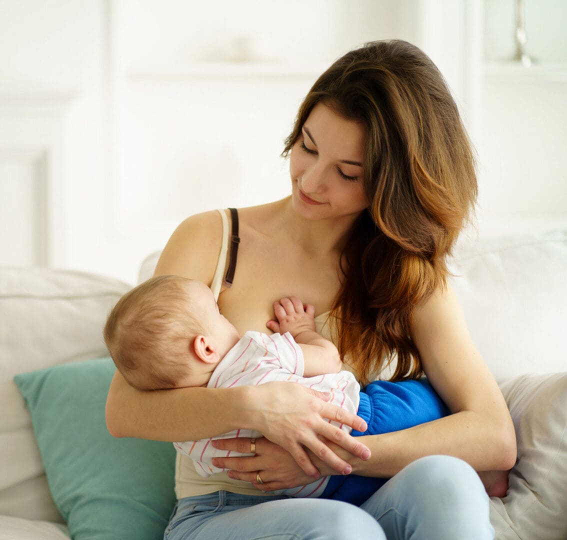 Mother breastfeeding baby on a couch.