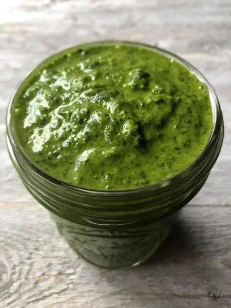 Green pesto in a glass jar.