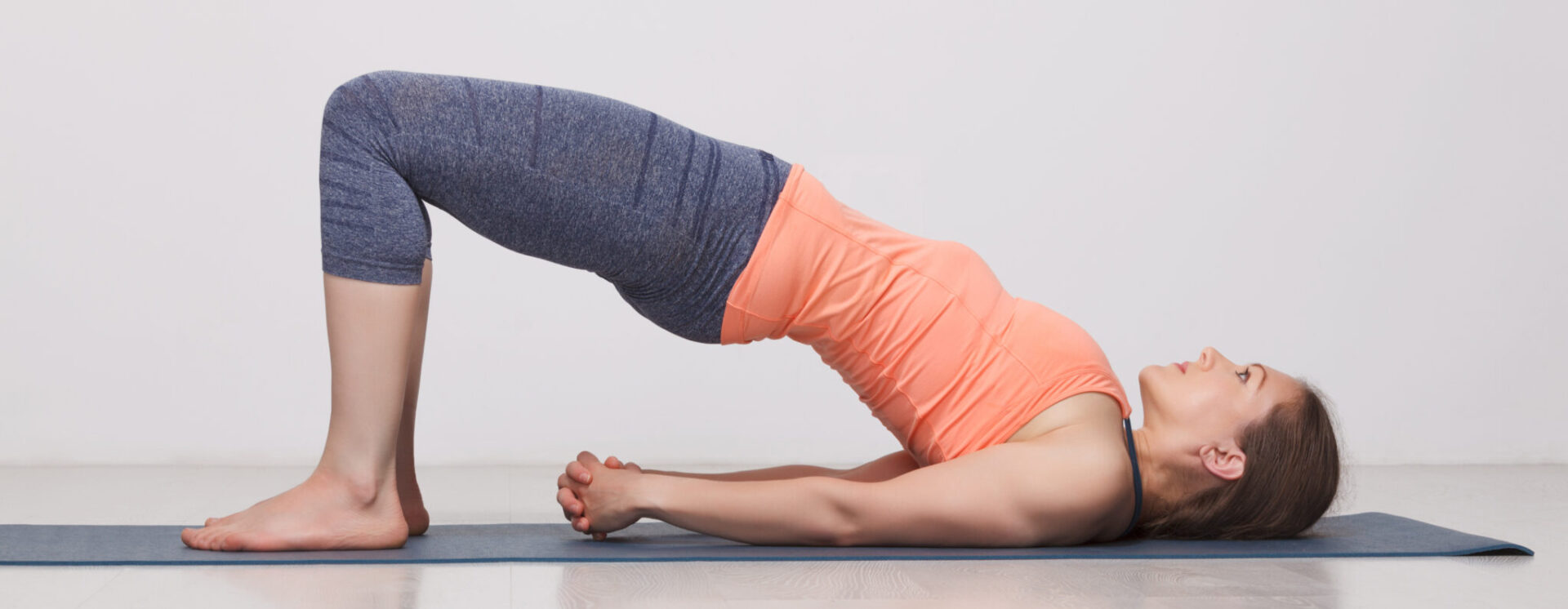 Woman doing a bridge pose on a mat.