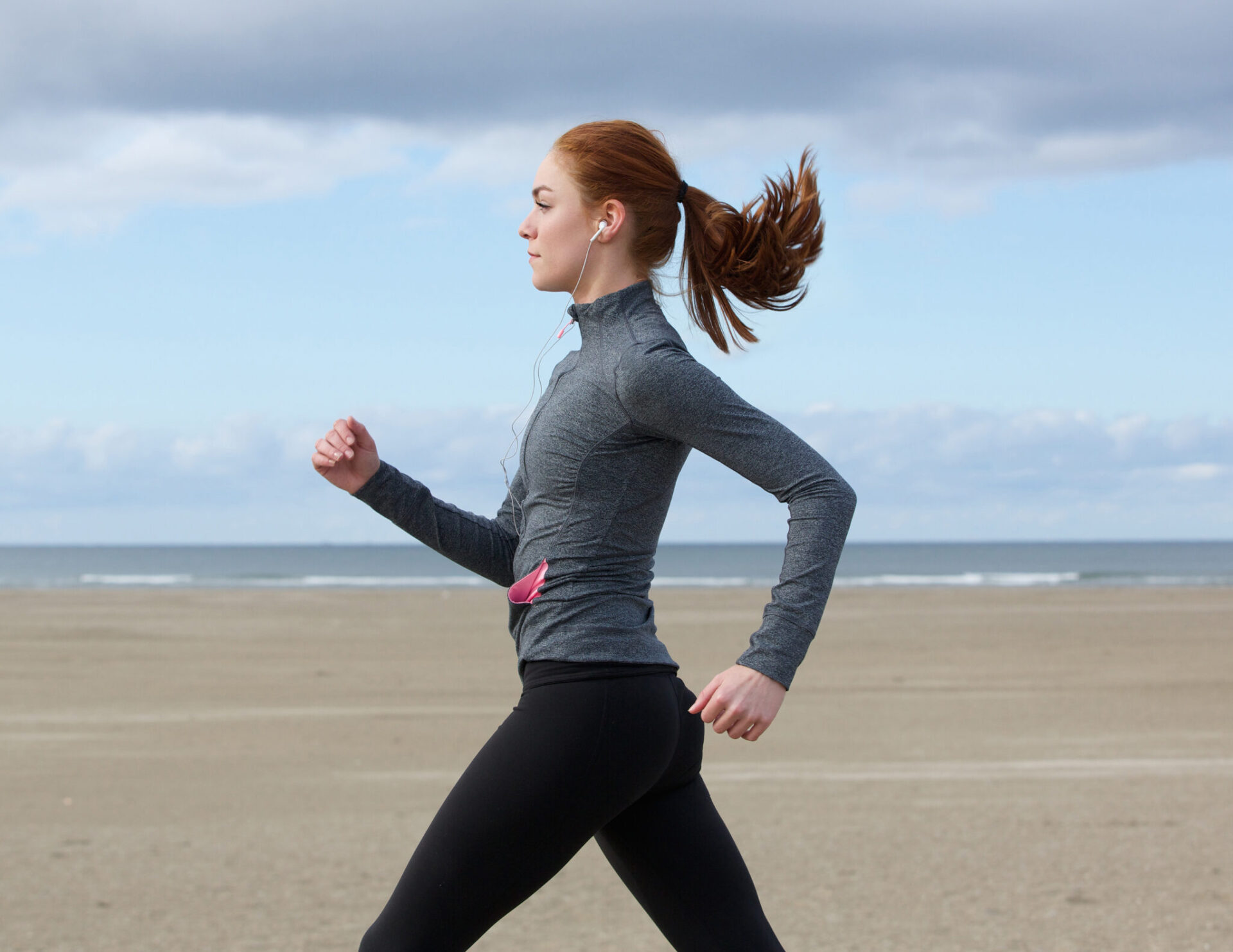 Woman jogging on a sandy beach.