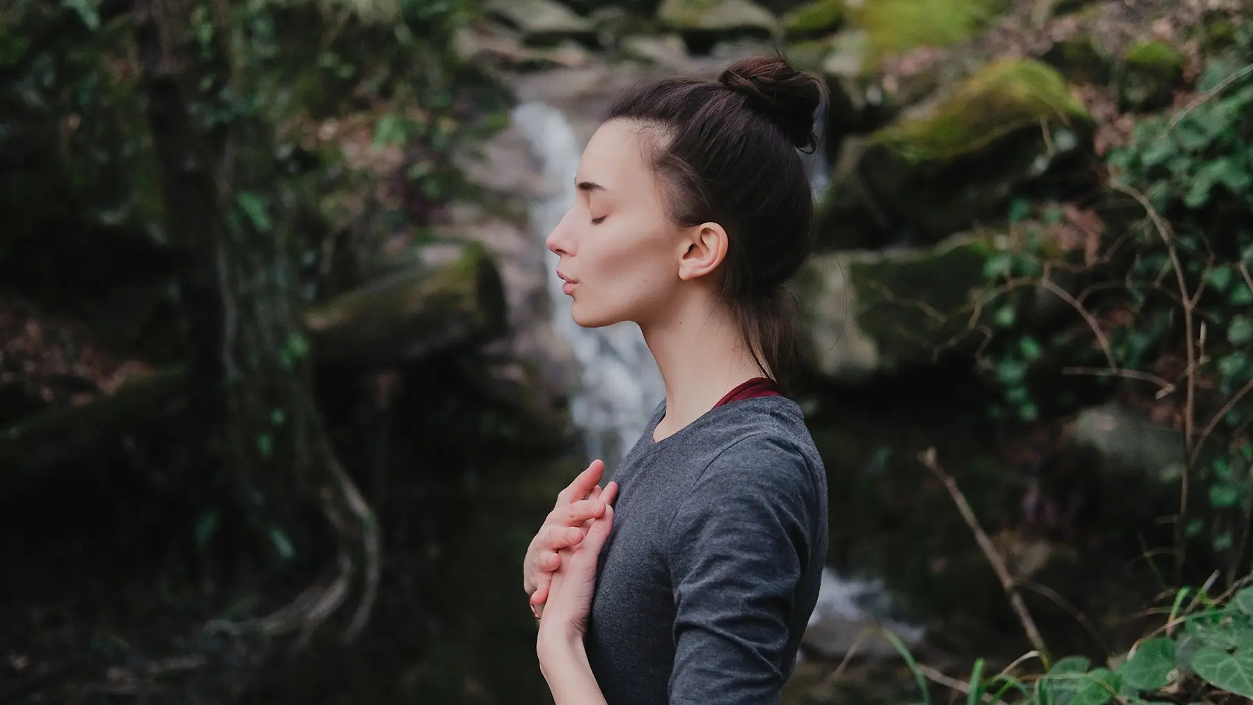 Woman meditating in a forest setting.