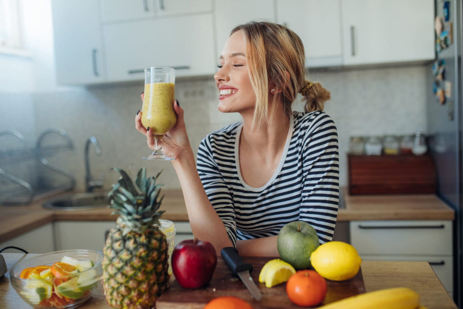 Woman enjoying a green smoothie in a kitchen.