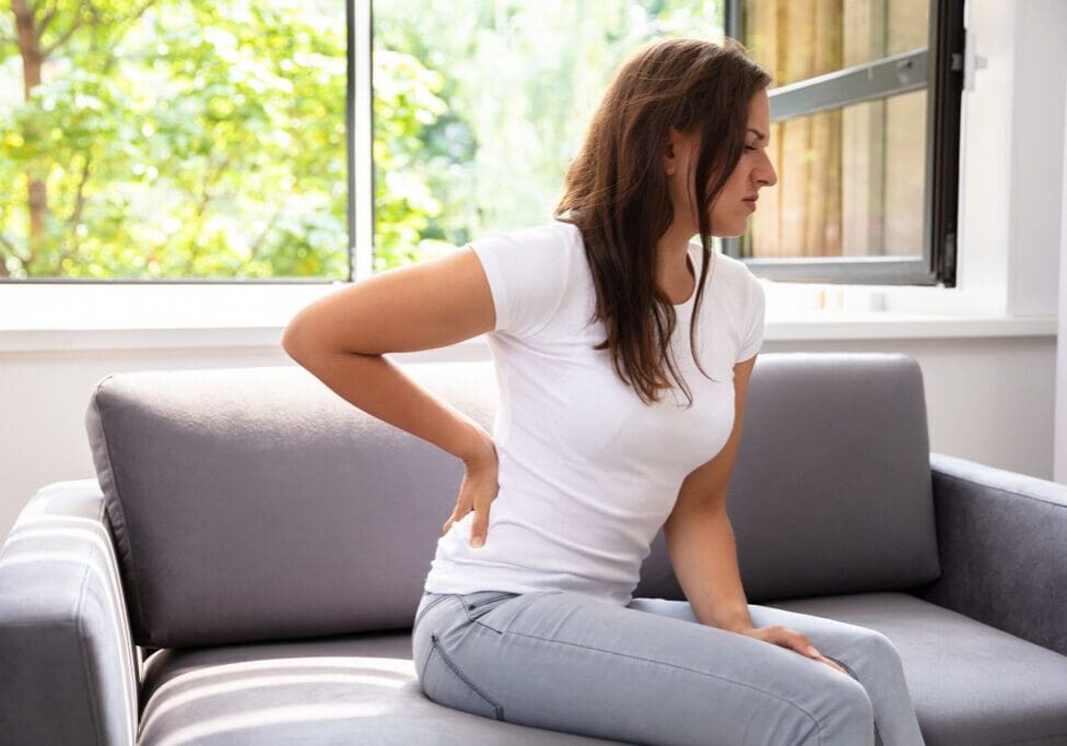 Woman sitting on couch with back pain.