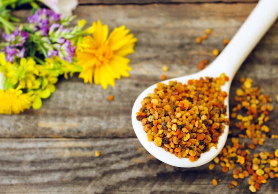 Spoon of bee pollen on wooden background.