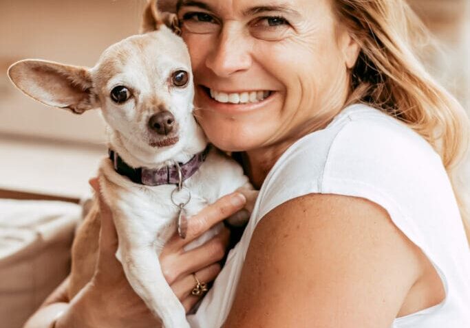 Woman smiling while holding a small dog.