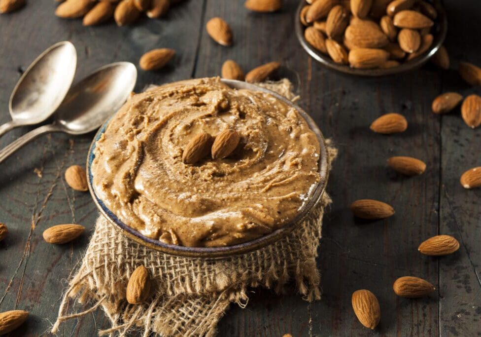 Almond butter in a bowl with almonds.