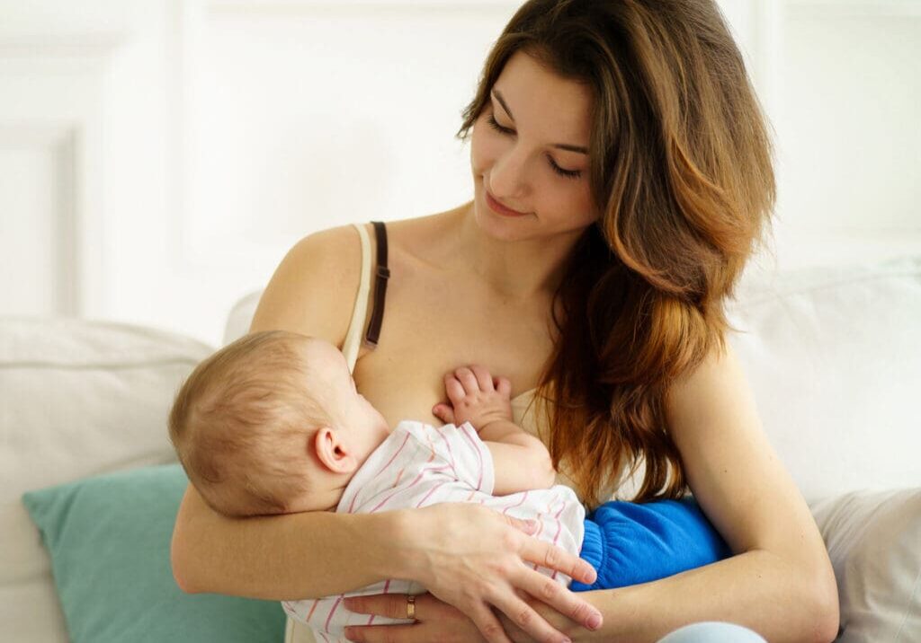 Mother breastfeeding baby on a couch.