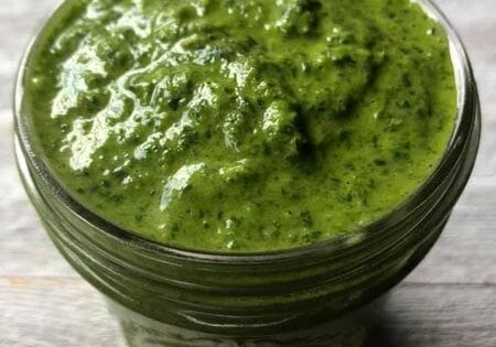 Green pesto in a glass jar.