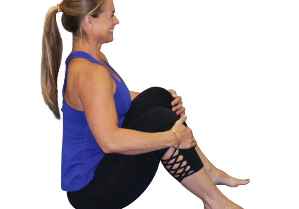 Woman in blue tank top sitting cross-legged.