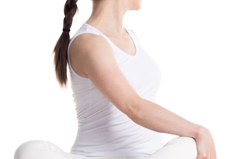 Woman in white seated with legs crossed.