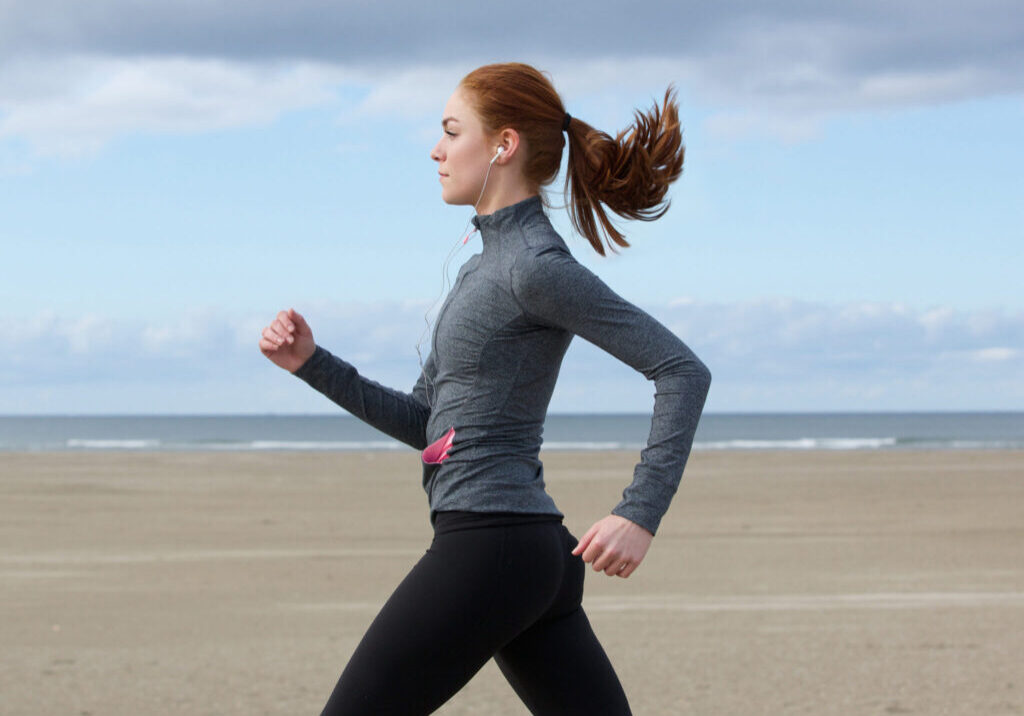 Woman jogging on a sandy beach.