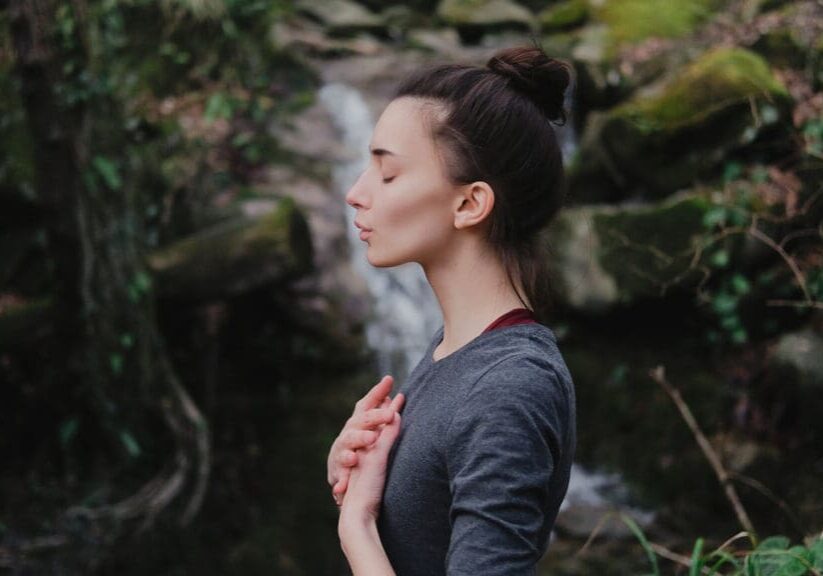 Woman meditating in a forest setting.