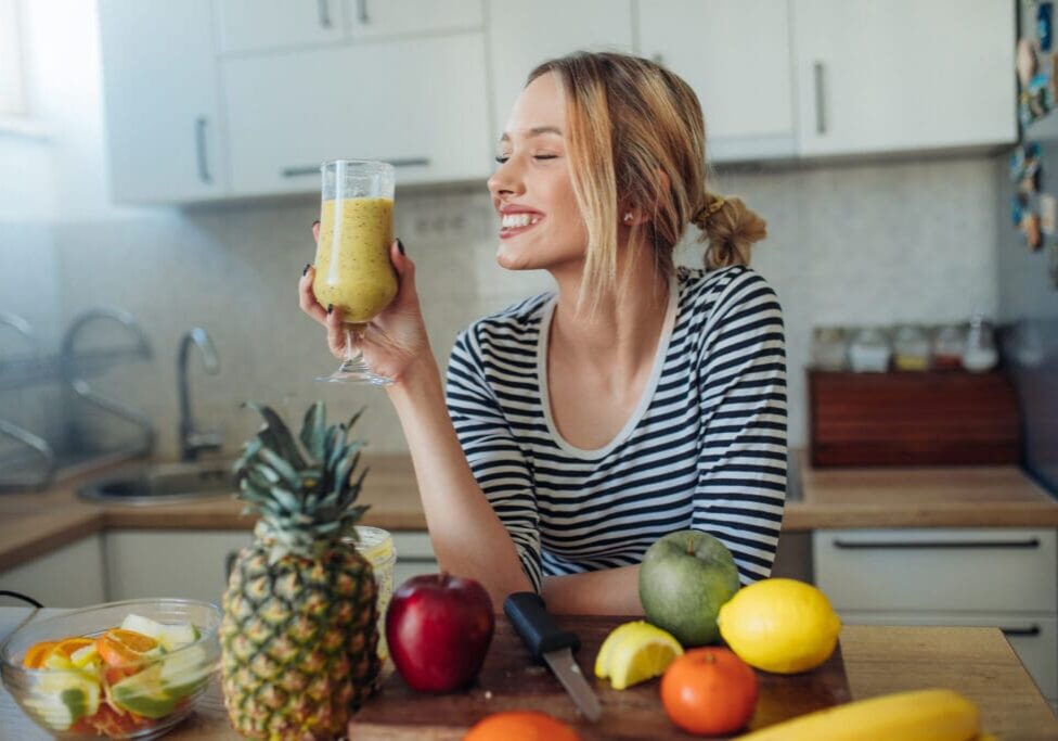 Woman enjoying a green smoothie in a kitchen.